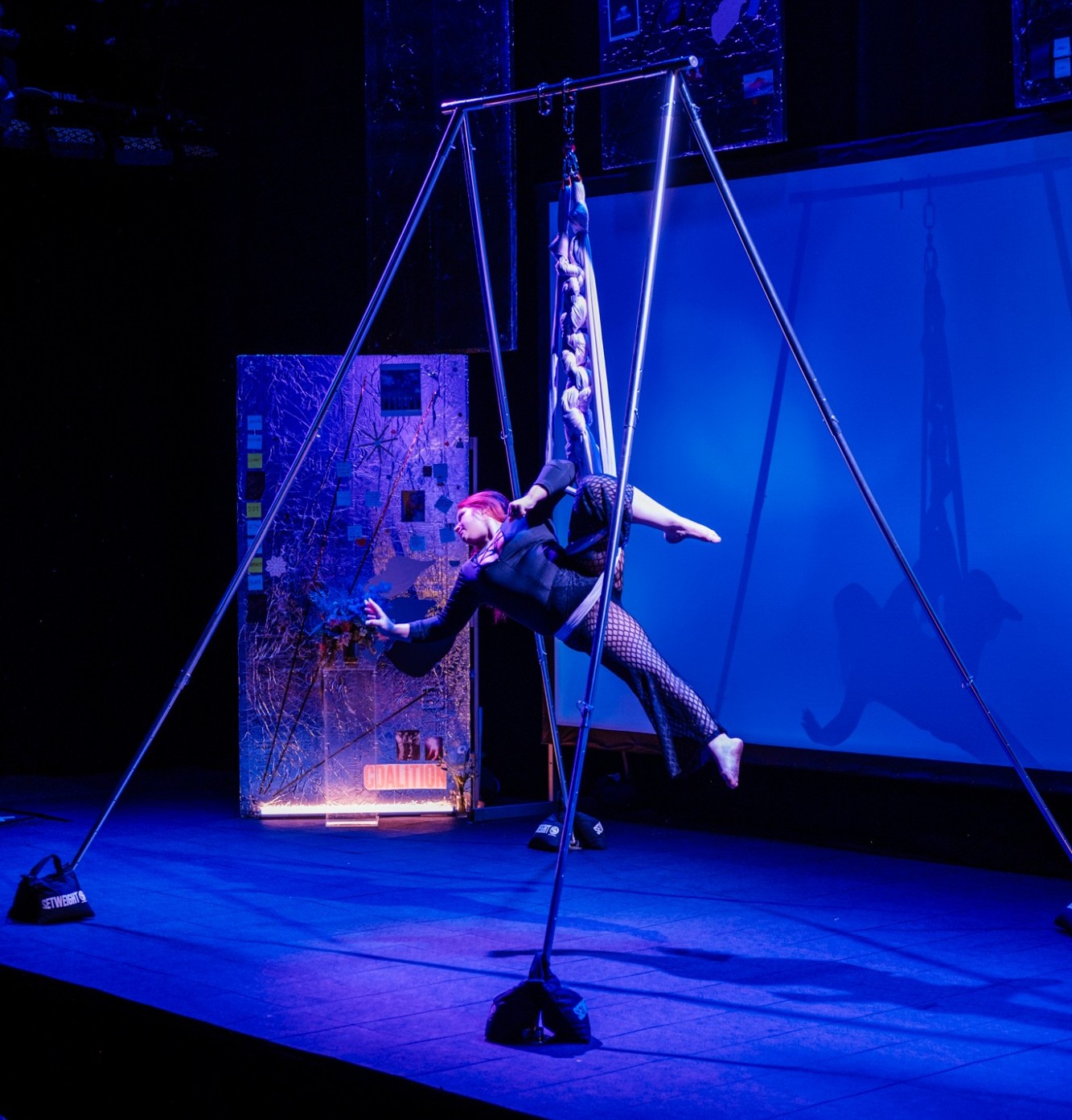 A woman on a stage in an aerial hammock
